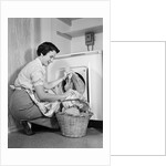 1950s Woman Kneeling Removing Clothes Laundry From Automatic Dryer by Anonymous