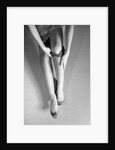 Woman's Hands Putting A Pair Of Sheer Stockings On Her Legs by Anonymous