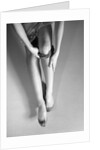 Woman's Hands Putting A Pair Of Sheer Stockings On Her Legs by Anonymous
