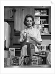 1960s Woman Housewife In Kitchen Checking Grocery Food Shopping List by Anonymous