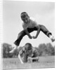 1960s Retro Boys Playing Leap Frog Outside Sky Grass Jump Jumping Crouching by Anonymous