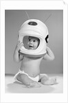 1960s Baby In Diaper Seated Holding Astronaut Helmet With Antennae On Head by Anonymous