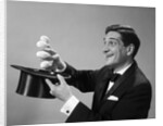 1960s Profile Magician Man Pulling 4 Eggs Out Of Hat Holding Them Between Fingers by Anonymous