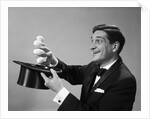 1960s Profile Magician Man Pulling 4 Eggs Out Of Hat Holding Them Between Fingers by Anonymous