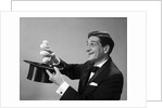 1960s Profile Magician Man Pulling 4 Eggs Out Of Hat Holding Them Between Fingers by Anonymous