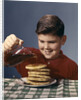 1950s 1960s Boy Pouring Syrup On Breakfast Pancakes by Anonymous