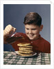 1950s 1960s Boy Pouring Syrup On Breakfast Pancakes by Anonymous