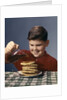 1950s 1960s Boy Pouring Syrup On Breakfast Pancakes by Anonymous