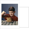 1950s 1960s Boy Pouring Syrup On Breakfast Pancakes by Anonymous