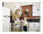 1970s Mother Handing Glass Of Milk To Son In Kitchen by Anonymous