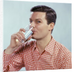 1960s Man Drinking Glass Water Wearing Red Checkered Shirt by Anonymous
