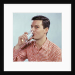 1960s Man Drinking Glass Water Wearing Red Checkered Shirt by Anonymous