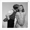 1950s 1960s Boy In Vest and Bow Tie Holding Valentine Candy Kissing Cheek Of Girl Making A Face by Anonymous