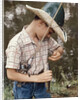 Boy Wearing Straw Hat Removing Hook From Mouth Of Fish Outdoor by Anonymous