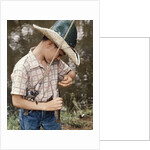 Boy Wearing Straw Hat Removing Hook From Mouth Of Fish Outdoor by Anonymous