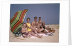 1960s Family On Sunny Beach Under Umbrella With Picnic Basket by Anonymous