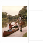 1960s Young Couple Loading Picnic Basket Thermos Into Canoe by Anonymous