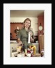 1960s Young Housewife While Checking Grocery Shopping Receipt In Kitchen by Anonymous