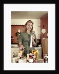 1960s Young Housewife While Checking Grocery Shopping Receipt In Kitchen by Anonymous