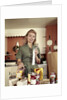 1960s Young Housewife While Checking Grocery Shopping Receipt In Kitchen by Anonymous