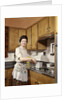 1960s Woman Housewife Wearing An Apron Stirring Cooking Pot At Kitchen Stove by Anonymous