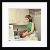 1970s Woman Housewife Homemaker Wearing Apron Loading Laundry Into Washing Machine by Anonymous