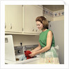 1970s Woman Housewife Homemaker Wearing Apron Loading Laundry Into Washing Machine by Anonymous