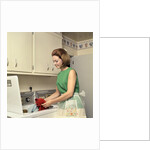 1970s Woman Housewife Homemaker Wearing Apron Loading Laundry Into Washing Machine by Anonymous