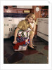 1960s Weary Dejected Woman Housewife Homemaker Sitting On Full Laundry Basket In Kitchen by Anonymous