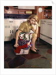 1960s Weary Dejected Woman Housewife Homemaker Sitting On Full Laundry Basket In Kitchen by Anonymous
