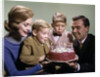 1960s Mother And Father Holding Birthday Cake And Sons Blowing Out Candles by Anonymous
