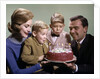 1960s Mother And Father Holding Birthday Cake And Sons Blowing Out Candles by Anonymous