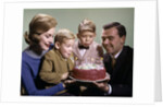 1960s Mother And Father Holding Birthday Cake And Sons Blowing Out Candles by Anonymous