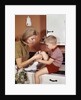 1970s Mother Giving First-Aid Putting Band-Aid On Knee Of Son In Kitchen by Anonymous