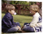 1970s Girls Sit Face To Face Blowing Pink Bubbles With Bubble Gum by Anonymous