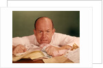 1960s Angry Man Businessman Desk Full Of Bills Paper Work Office Stress Frustration by Anonymous
