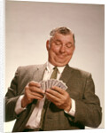 1960s Satisfied Man Looking At Hand Of Playing Cards by Anonymous