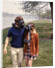 1970s Young Romantic Teenage Couple Man Woman Wearing Gas Masks Walking By River by Anonymous