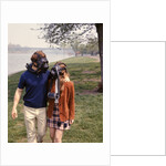 1970s Young Romantic Teenage Couple Man Woman Wearing Gas Masks Walking By River by Anonymous