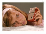 1950s 1960s Teenage Girl Holding Red Silver Small Transistor Radio To Her Ear Listening by Anonymous