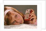 1950s 1960s Teenage Girl Holding Red Silver Small Transistor Radio To Her Ear Listening by Anonymous