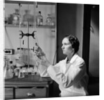 1930s 1940s Woman Scientist In Lab Coat Holding Up And Examining Beaker Of Liquid by Anonymous