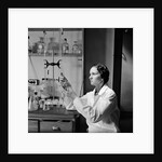 1930s 1940s Woman Scientist In Lab Coat Holding Up And Examining Beaker Of Liquid by Anonymous