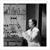 1930s 1940s Woman Scientist In Lab Coat Holding Up And Examining Beaker Of Liquid by Anonymous