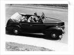 1930s 1940s Couple Driving 1938 Convertible Four Door Sedan Automobile With Luggage In Back Seat by Anonymous