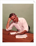 1970s Middle Age Man Sitting At Desk Worried About Bills To Pay by Anonymous