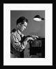 1940s Young Man Office File Clerk Putting Records Into Filing Cabinet Drawer by Anonymous