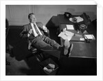 1950s Man Businessman Salesman Eating Lunch In Office With Feet Resting Up On Desk by Anonymous