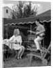 1960s Boy Playing Guitar, Woman Holding Soft Drink Bottle Outside In Backyard by Anonymous