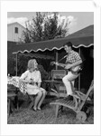 1960s Boy Playing Guitar, Woman Holding Soft Drink Bottle Outside In Backyard by Anonymous
